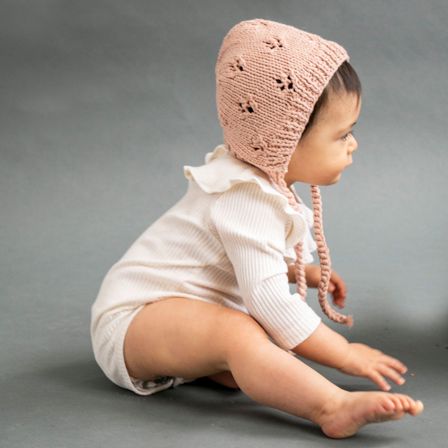 hand knit dusty pink cotton bonnet with openwork stitching and tie closure