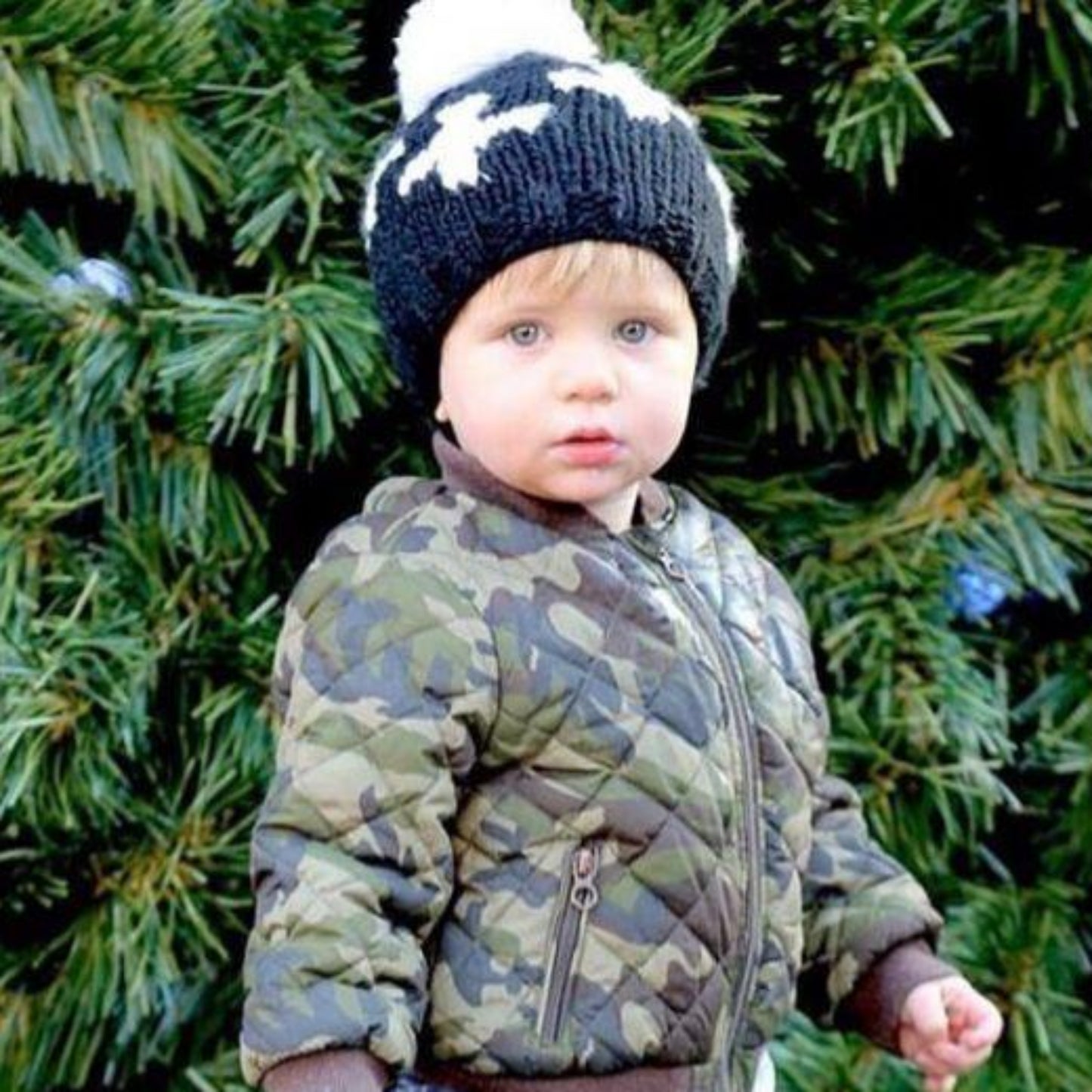 black hand knit beanie with white pom and and swiss cross pattern