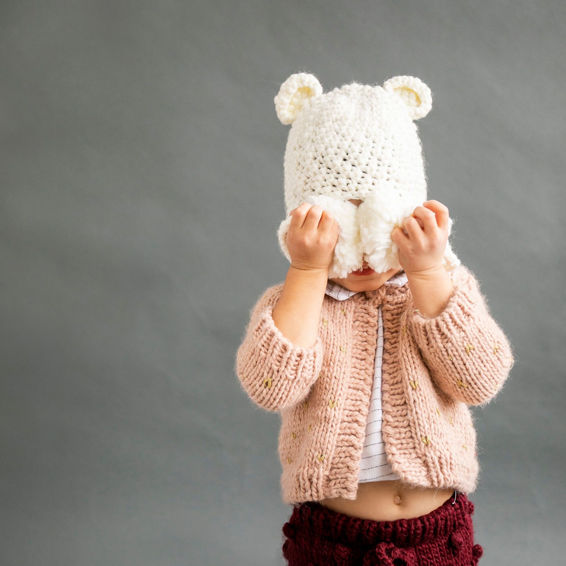 crochet bear hat with ears and pom tassels for baby and toddler cream